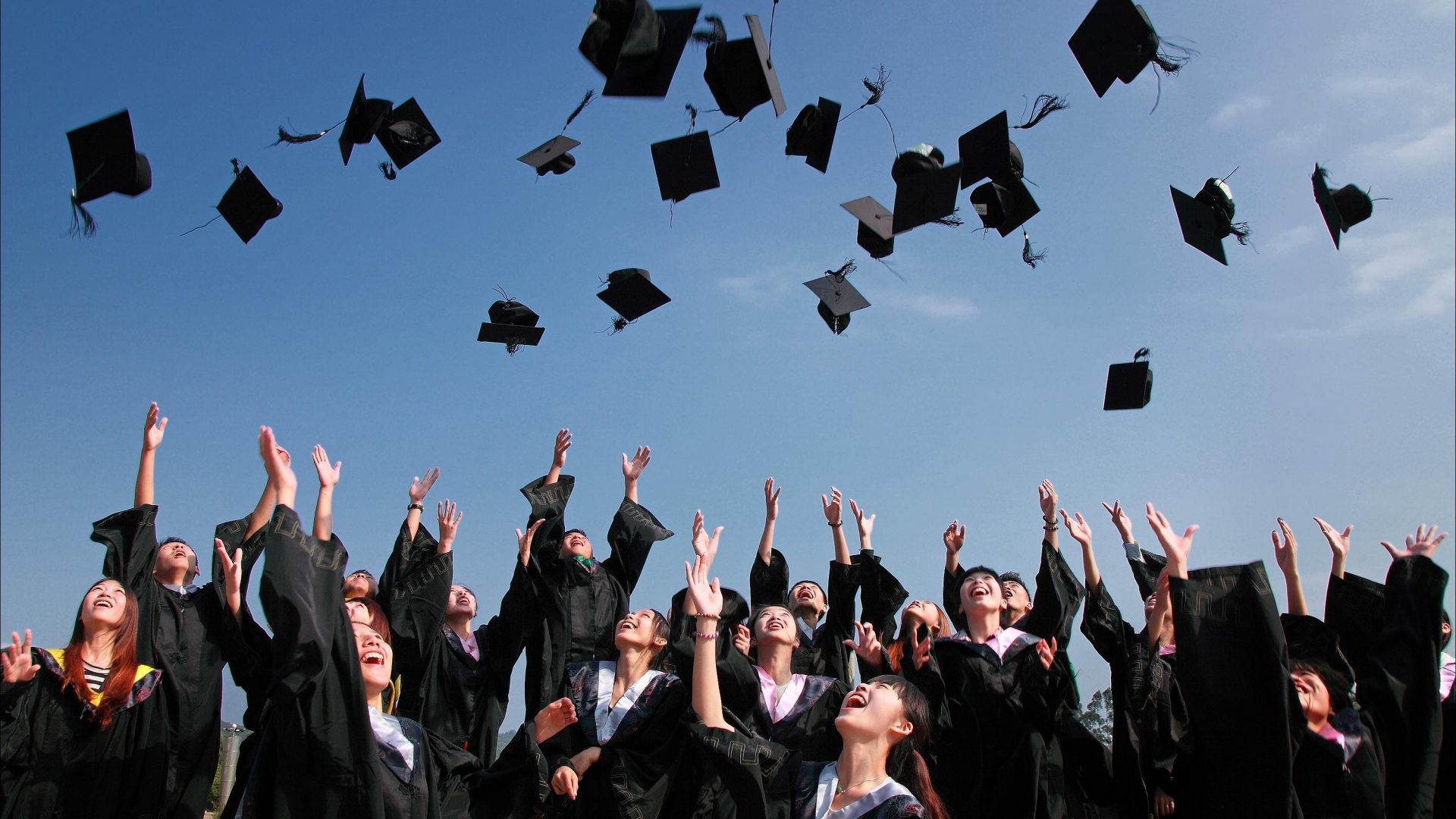 Group of graduates throwing hats into air