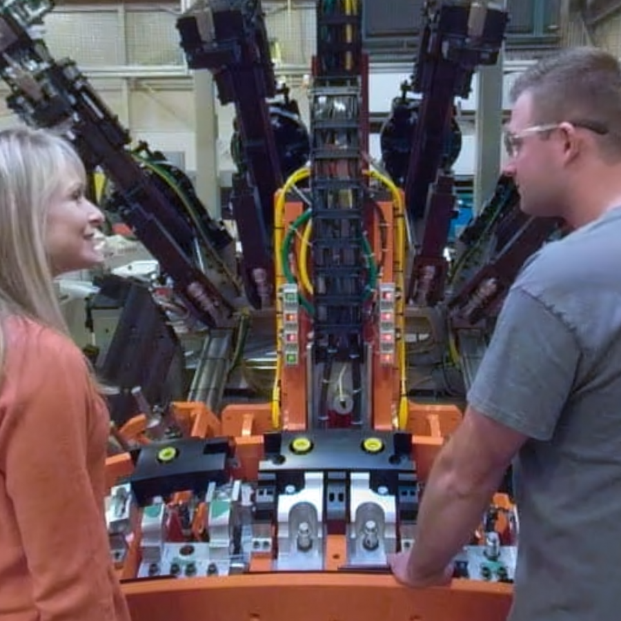 Two people in front of machinery at a manufacturing facility
